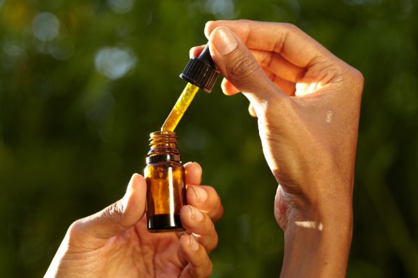 woman holding a dropper with an oil product bottle